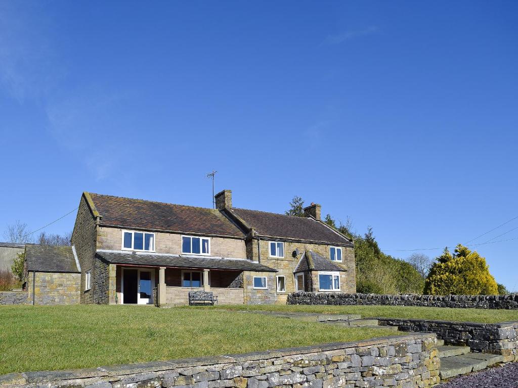 a large stone house with a stone wall at Broadmeadows Farm in Butterton