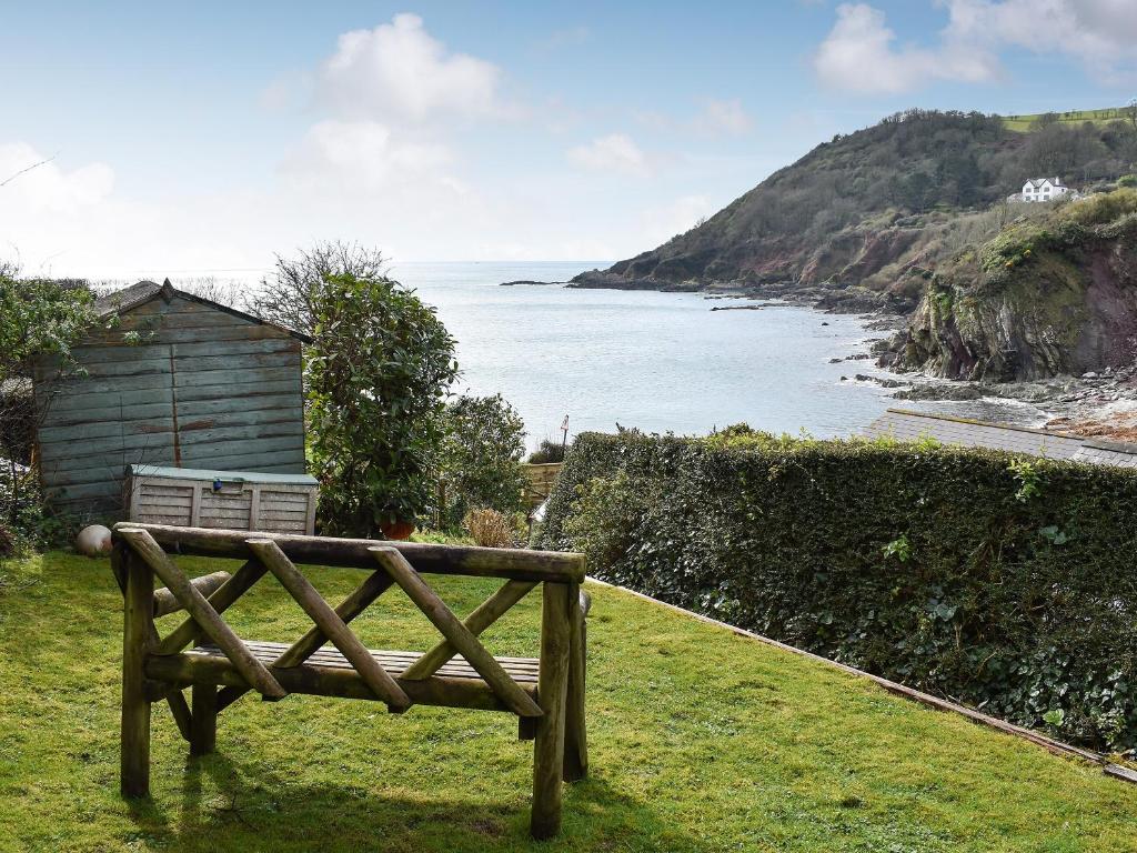 a wooden bench sitting in the grass near the ocean at Sea View - Uk30589 in Polperro