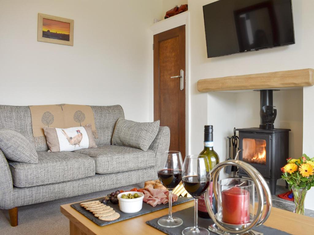 a living room with a couch and a table with wine glasses at Manor Park Cottage in Knitsley