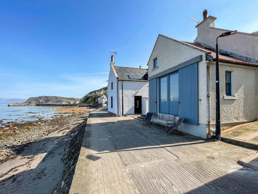 a building with a bench next to the water at Fishermans Cottage in Gardenstown