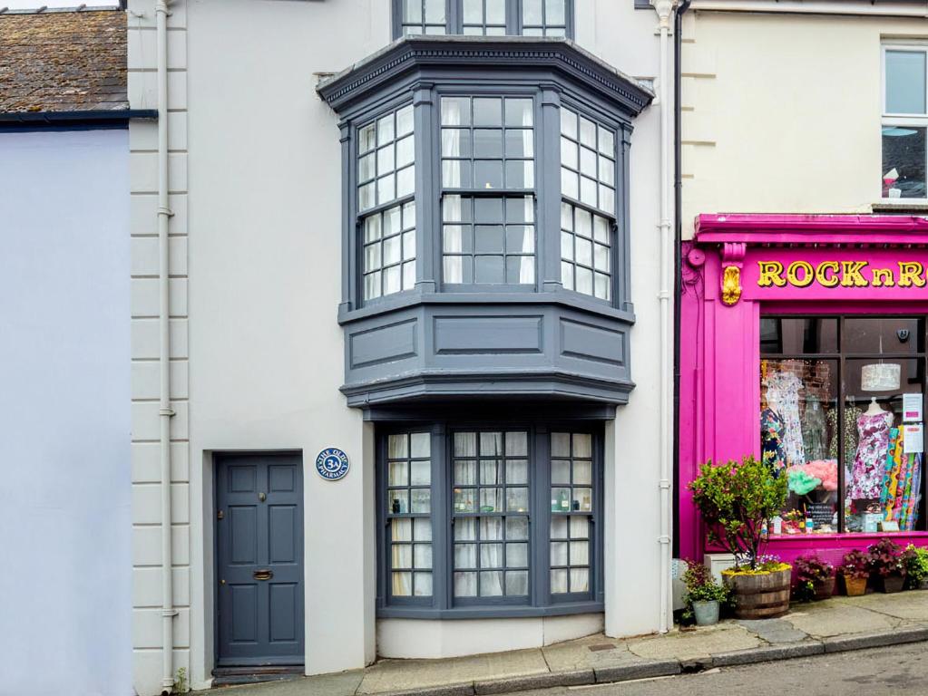un edificio blanco con puertas azules y una tienda rosa en The Old Pharmacy, en Narberth