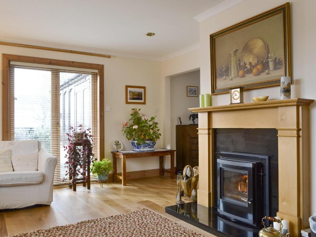a living room with a fireplace and a couch at Rowan Cottage in Aviemore