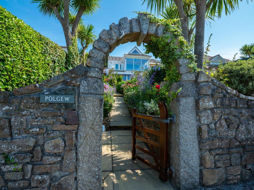 a stone wall with a gate in front of a house at Polgew Apartment in Marazion