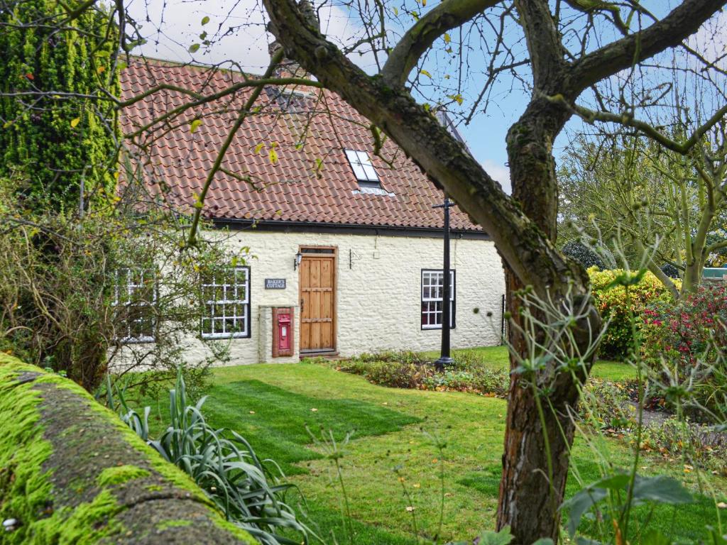 una casa de ladrillo blanco con puerta roja en Bakers Cottage en Hotham