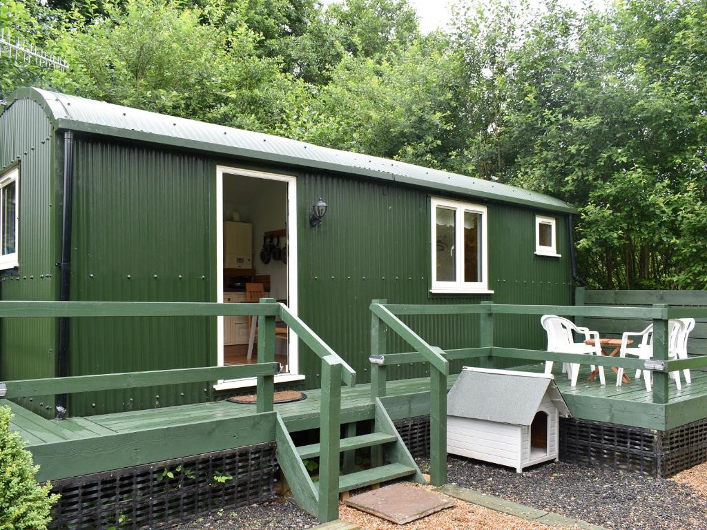 a green tiny house with a staircase and a porch at Shepherds Hut 3 At Laddingford - Uk32532 in Yalding