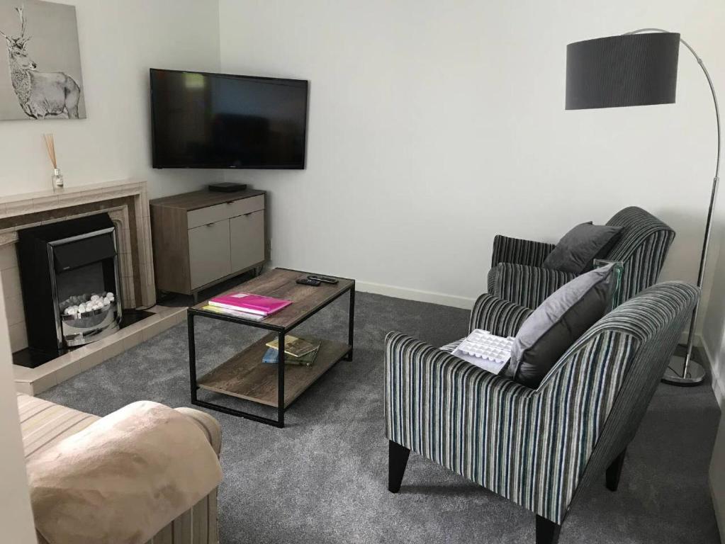 a living room with a tv and a chair and a table at The Cottage 47 in Aird Tong