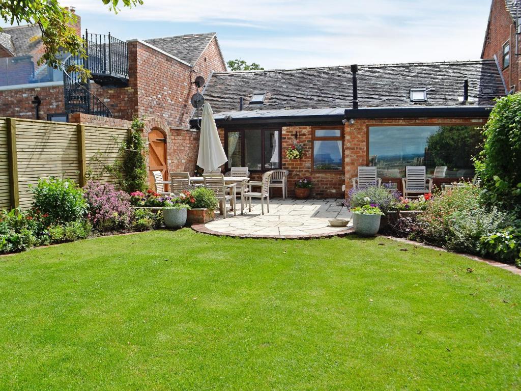 a garden with a patio with an umbrella and a lawn at The Cottage in Cheltenham