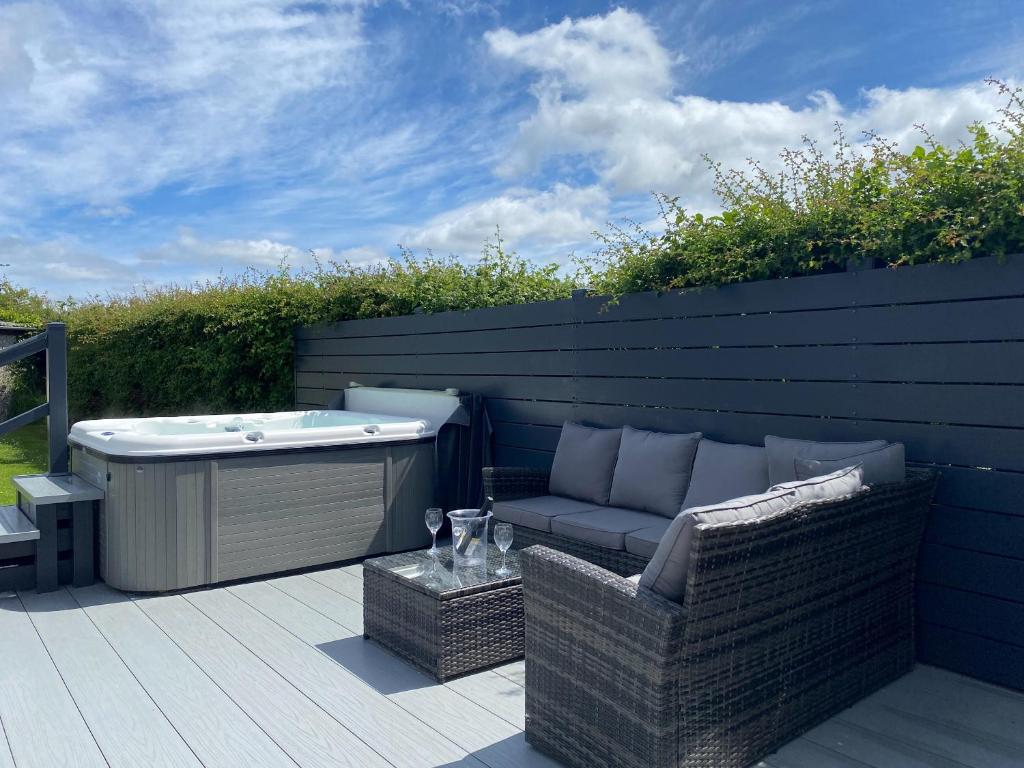 a patio with a hot tub and wicker chairs at White Towers - Hw7625 in Llanwnda