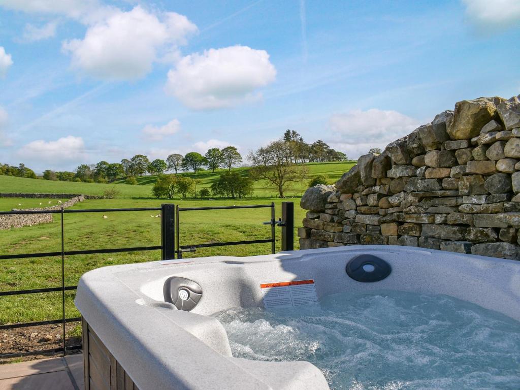 a jacuzzi tub sitting next to a stone wall at Tormire Laithe in Bell Busk