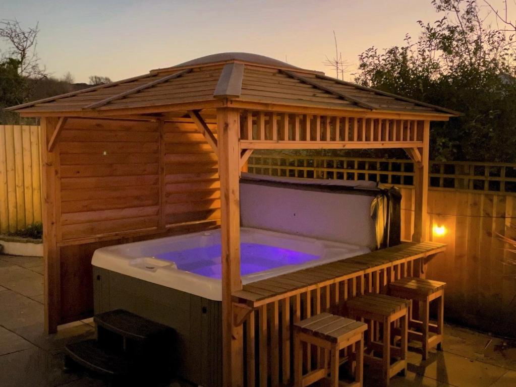 a hot tub in a wooden gazebo with stools around it at Oakwood in Saint Endellion
