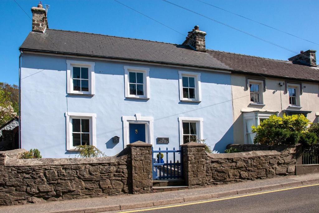 a blue and white house with a stone wall at The Old Police House in Fishguard