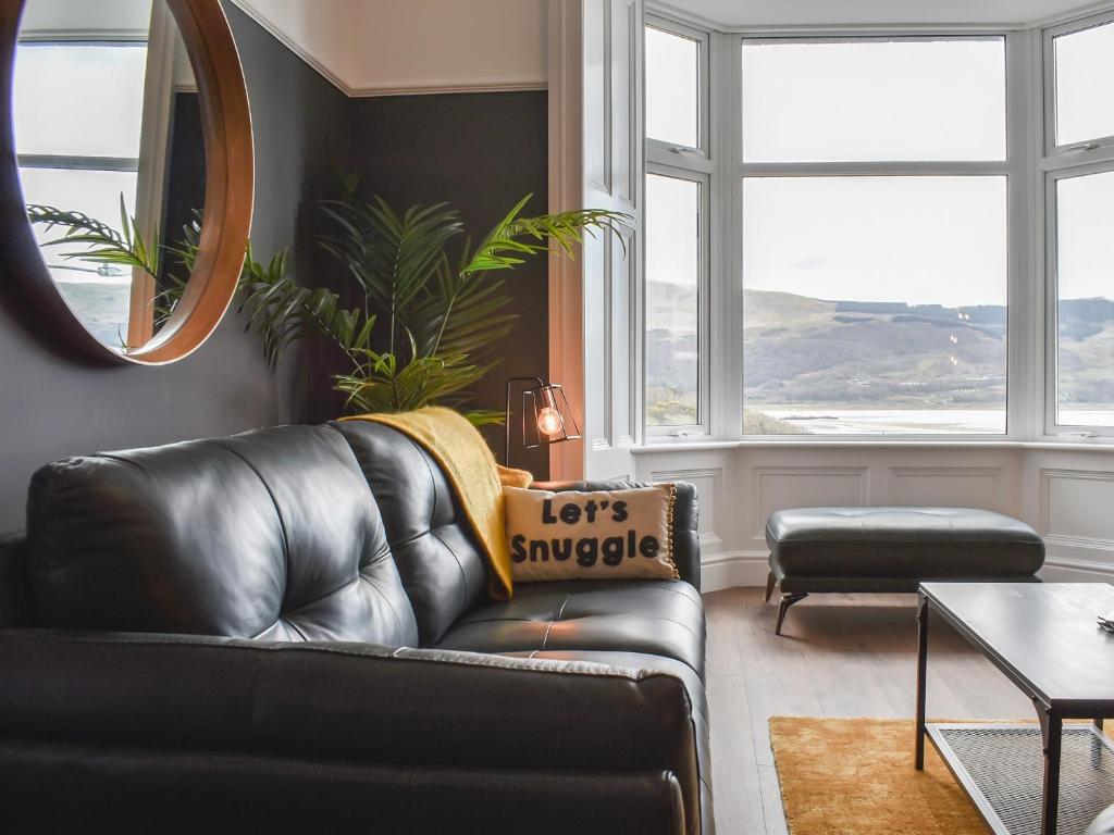 a living room with a leather couch and a mirror at Ty Isaf in Barmouth