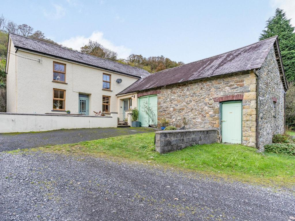 an old stone house with a garage and a driveway at Pwll Farmhouse in Llanllawdog