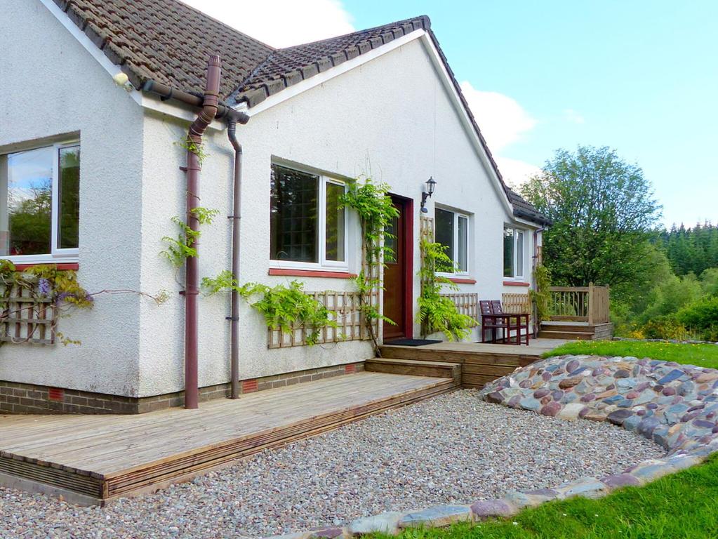 a house with a wooden porch and a deck at Bo Nan Taigh Cottage in Aberfoyle