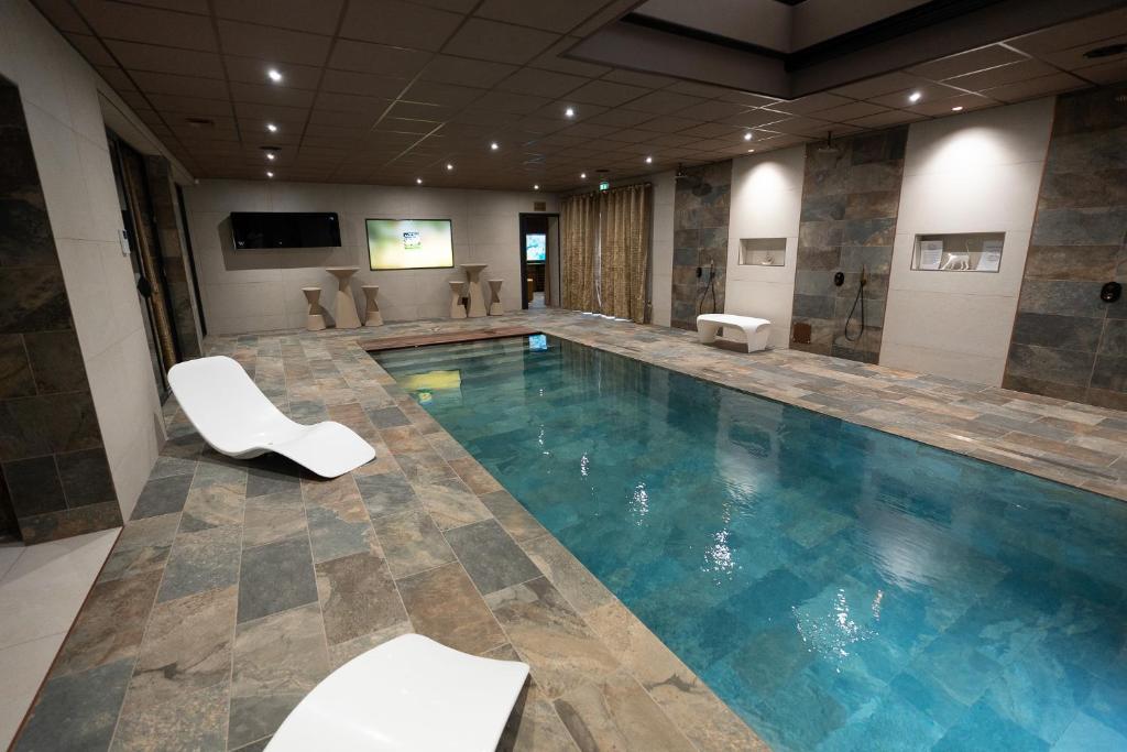 - une piscine avec 2 chaises blanches dans une chambre dans l'établissement CARACALLA PRIVE - Chambres d'hôtes avec Piscine, Jaccuzi et Hammam privatifs, à Saint-Étienne