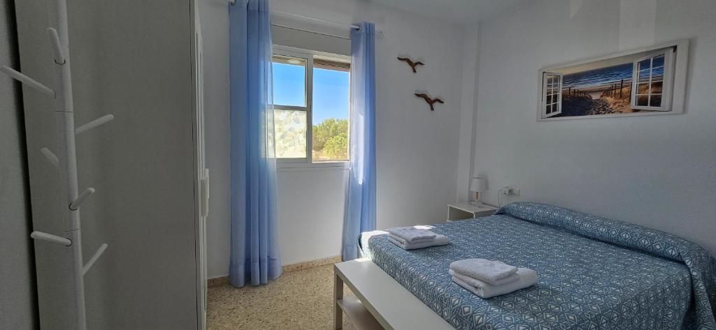 1 dormitorio con cama con sábanas azules y ventana en SOL Y PLAYA, en San Fernando