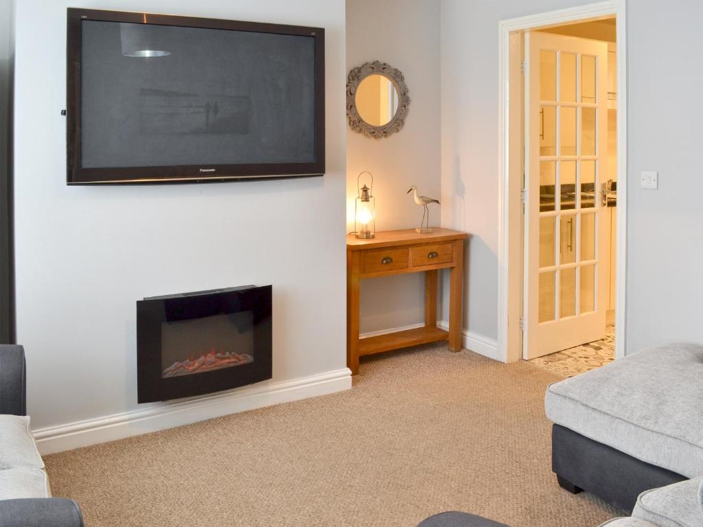 a living room with a fireplace and a flat screen tv at Seagulls Rest in Filey