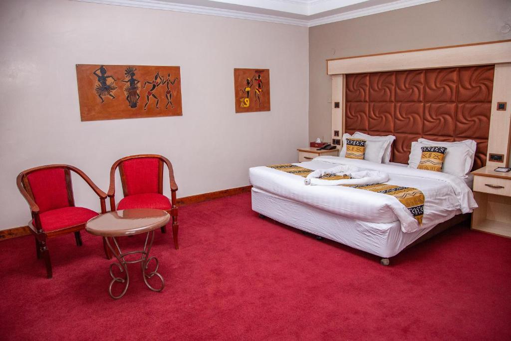 1 dormitorio con 1 cama grande y 2 sillas rojas en The Luke Hotel Cravers Thika, en Thika