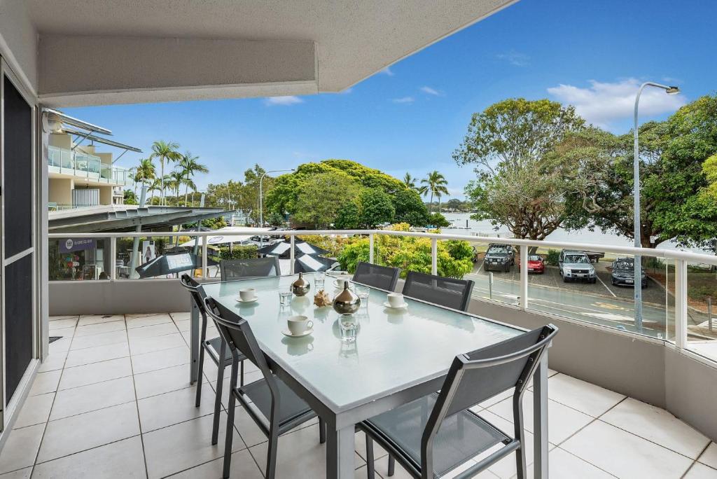 a table and chairs on a balcony with a view of a parking lot at 1 Riverside in Noosaville