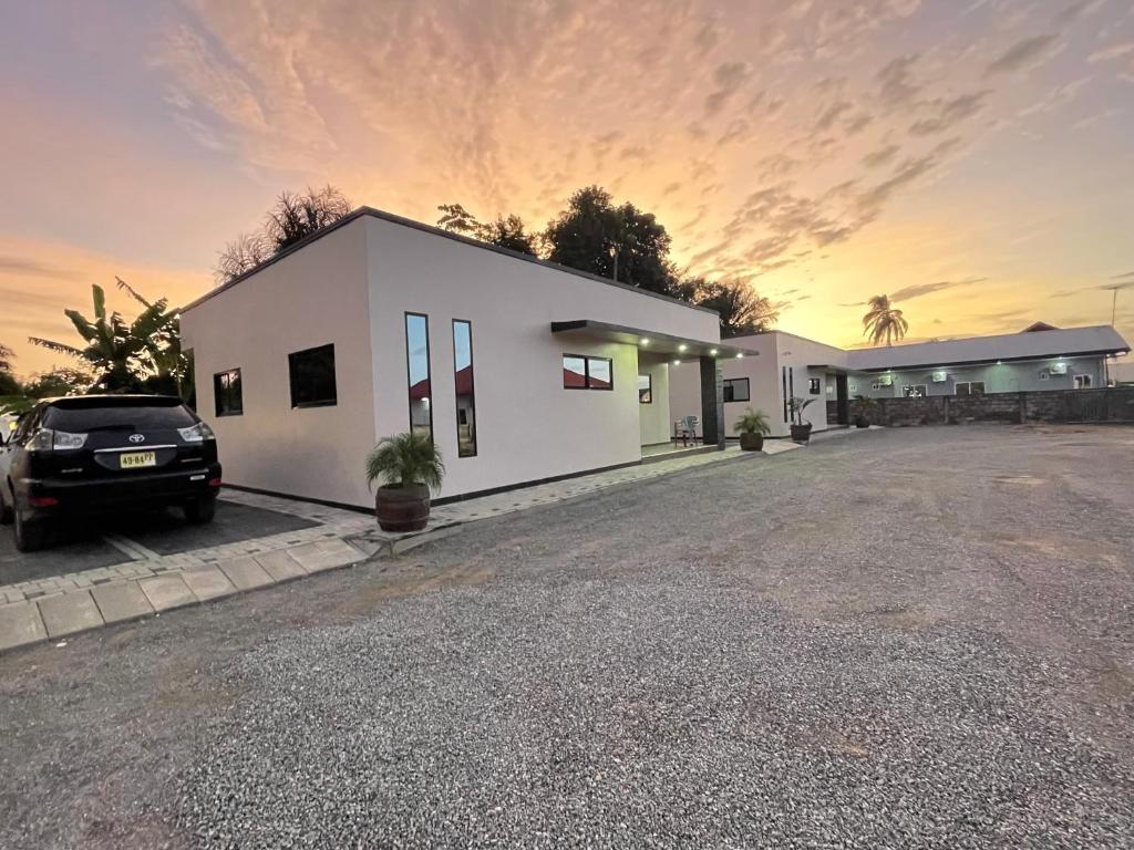 a white house with a car parked in a parking lot at Suriday Village in Wanica