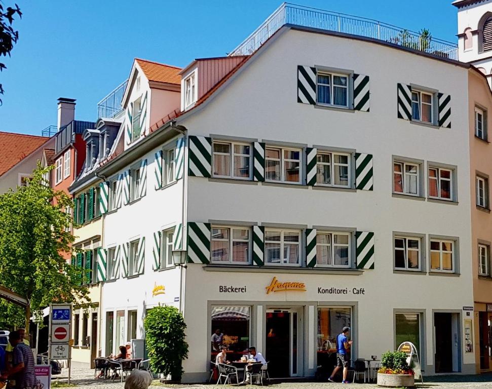 a large white building with people sitting outside of it at ADORIS FERIENWOHNUNGEN auf der Lindauer Insel in Lindau