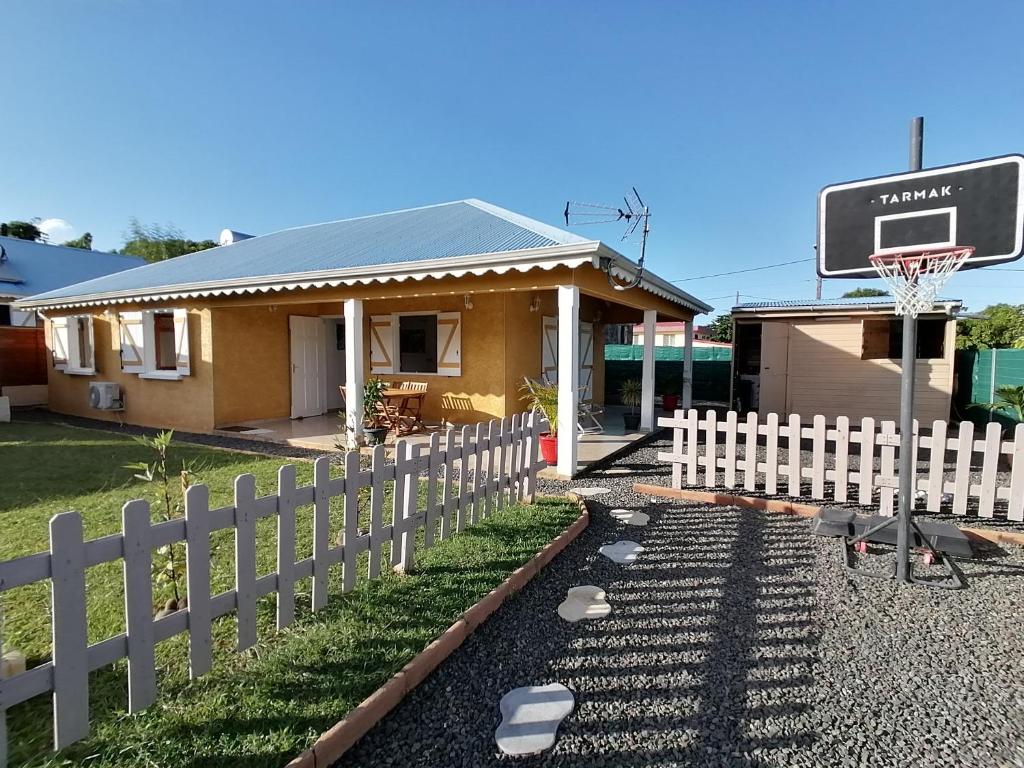 a house with a white picket fence and a basketball hoop at La villa karukera in Sainte-Rose