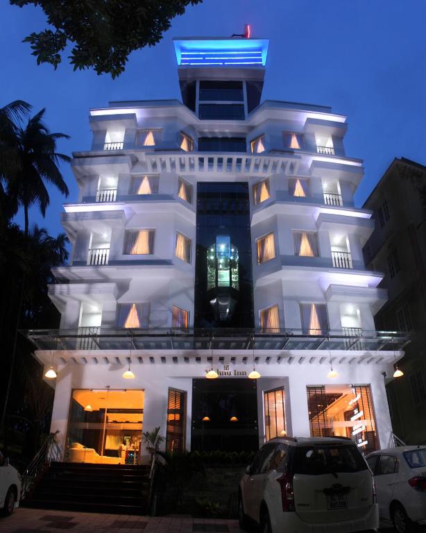 a white building with cars parked in front of it at Vishnu Inn in Guruvāyūr