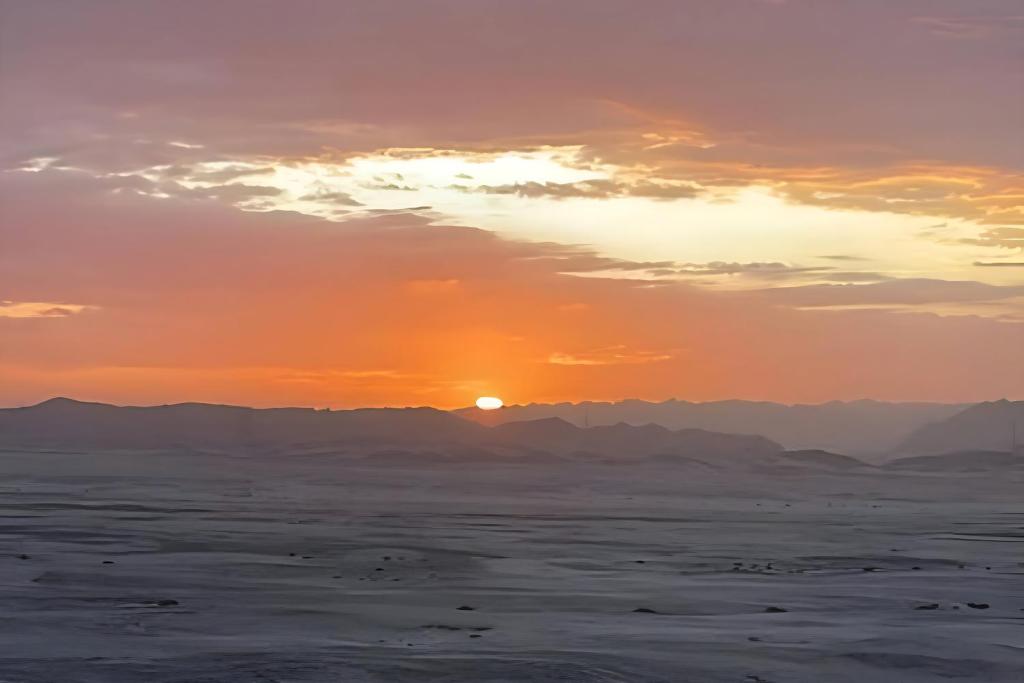 スワコプムントにあるMoon Landscape Self Cateringの山々を背景に砂漠に沈む夕日