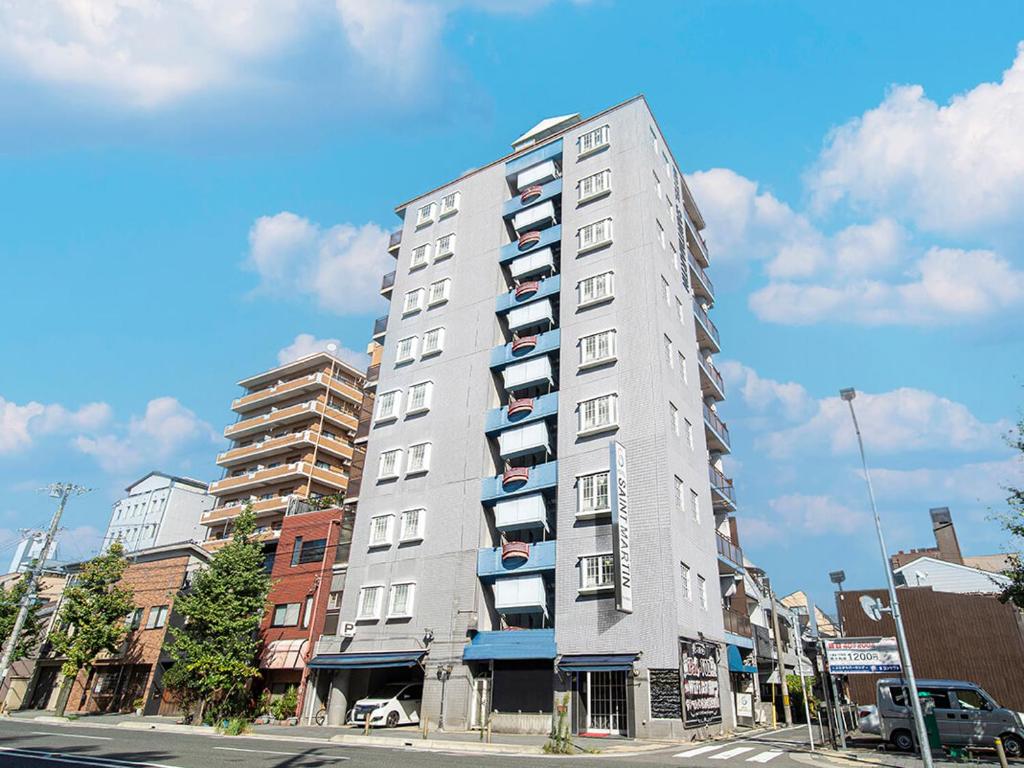 a tall white building with balconies on a city street at Saint martin (Adult Only) in Kyoto