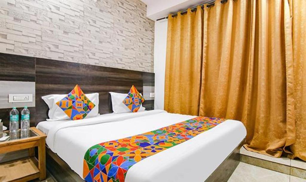 a bedroom with a large bed and a yellow curtain at FabHotel Shyam in Zirakpur