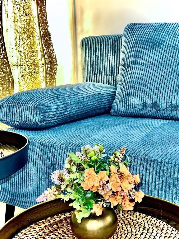 a blue couch with a vase of flowers on a table at GastRoom Am Seefeld in Grafing