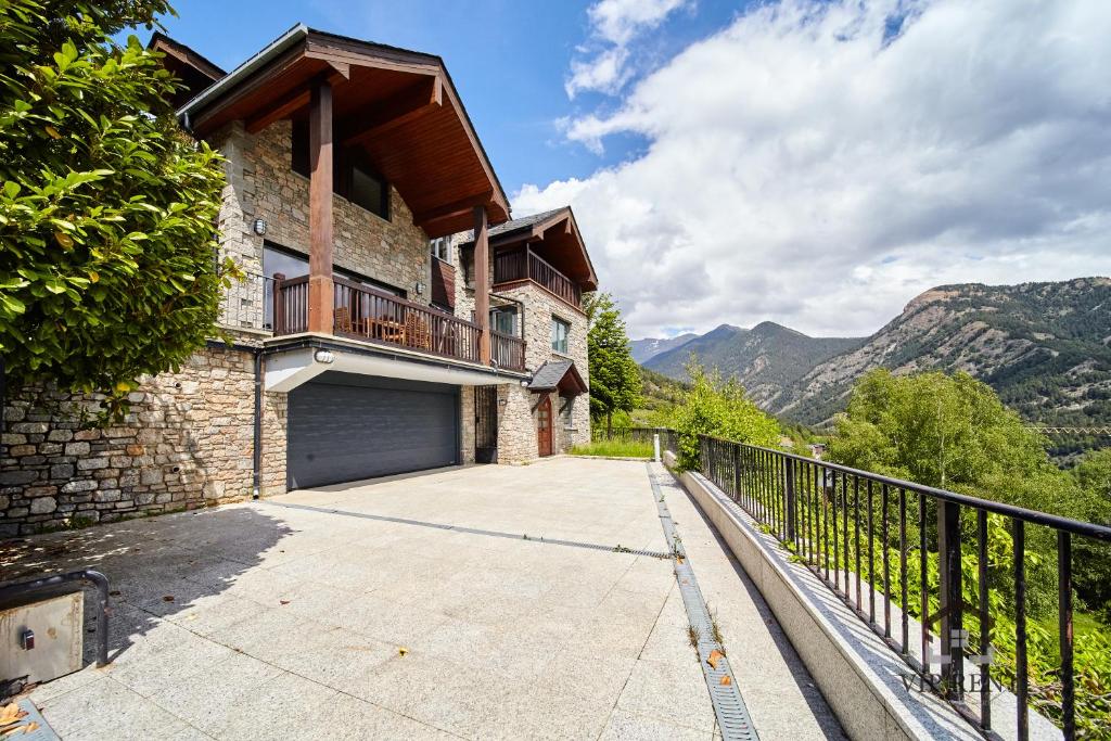a house with a garage and mountains in the background at Chalet el Salze 10 pax in La Massana