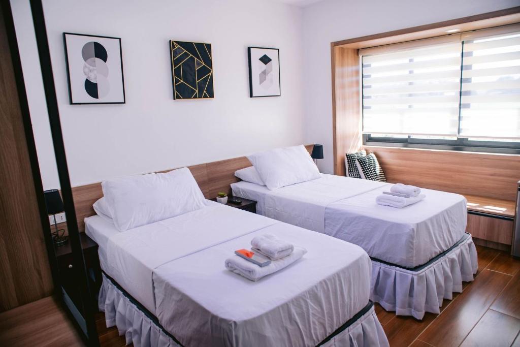 2 camas en una habitación con sábanas blancas y toallas en Dream Residences, en Manolo Fortich