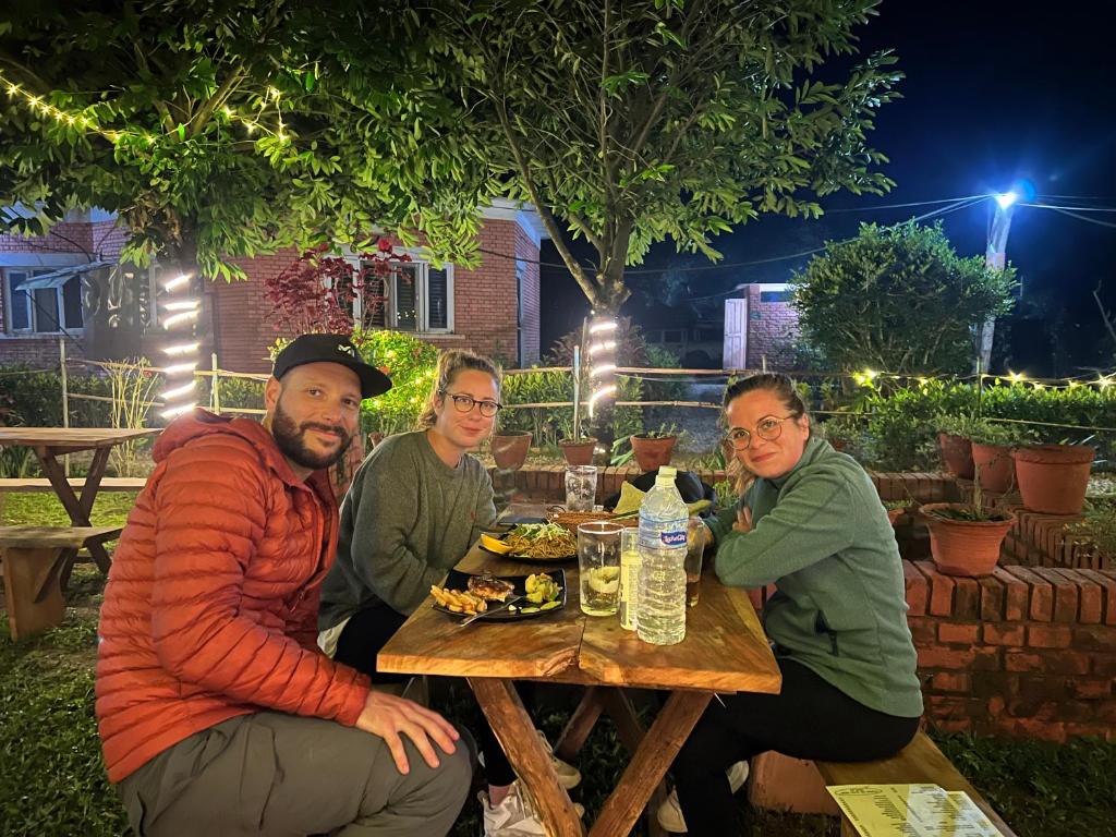 a group of people sitting at a table eating food at Hotel Tharu Garden And Beer Bar in Chitwan