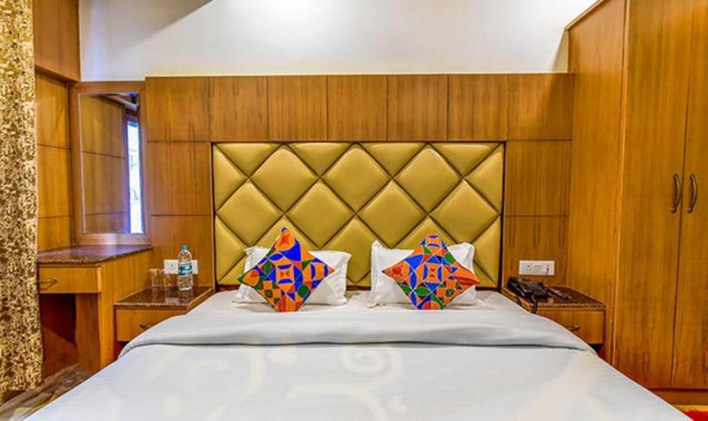 una camera da letto con un grande letto bianco con due cuscini di FabExpress Clock View 500M From The Mall Road a Mussoorie