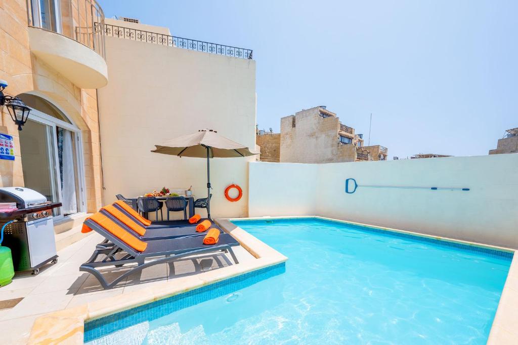 a swimming pool with a chair and an umbrella at Veduta Holiday Home in Qala