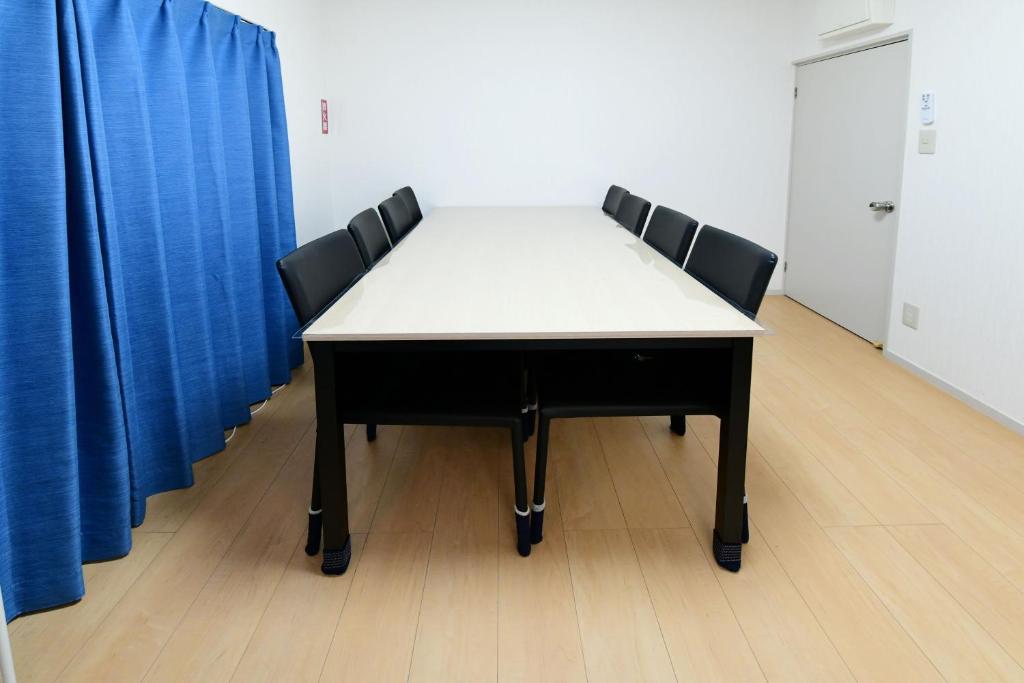 stół z 4 krzesłami w pokoju z niebieskimi zasłonami w obiekcie JH Yellow Guest House w Tokio
