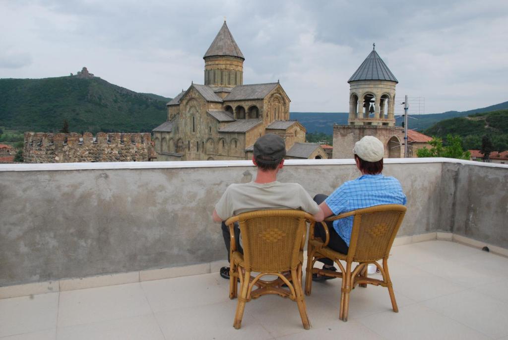 two people sitting on a balcony looking at an old building at Old Capital in Mtskheta