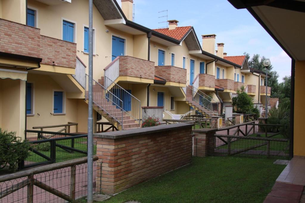 a row of apartment buildings with stairs and grass at Poolside escape in Rosolina mare - Beahost in Rosapineta