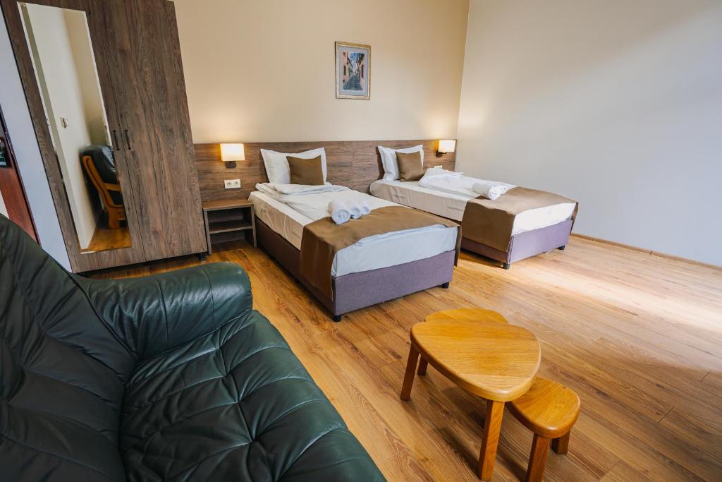 a hotel room with two beds and a couch at Хотел Театъръ in Pleven