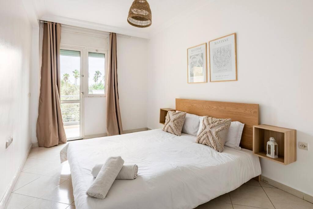 sypialnia z łóżkiem z białą pościelą i oknem w obiekcie Rabat Centro Apartments w mieście Rabat