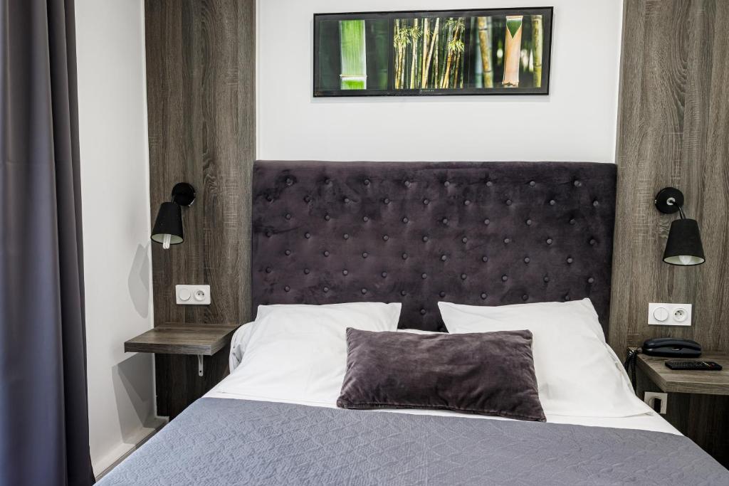 a bedroom with a large bed with a black headboard at Hotel Du Dauphiné in Lyon