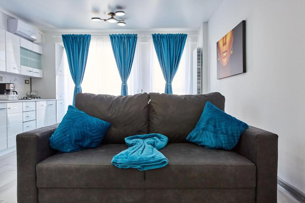 ein braunes Sofa mit blauen Kissen im Wohnzimmer in der Unterkunft Apartamente Nord 10 in Năvodari