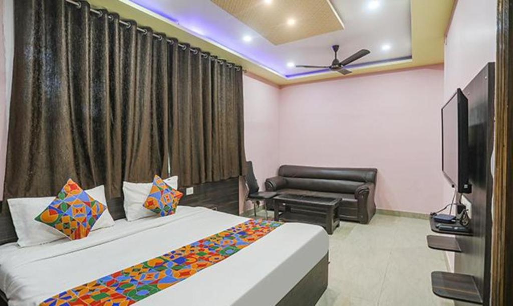 a bedroom with two beds and a couch and a television at FabExpress Banarasi Kothi in Varanasi