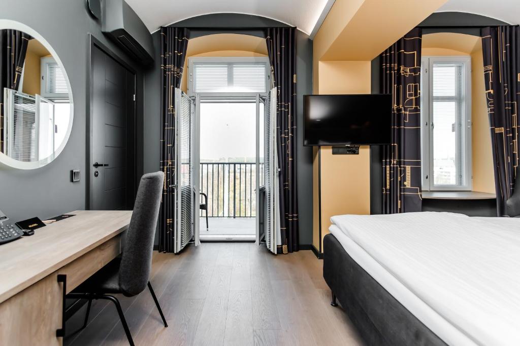 - une chambre avec un lit, un bureau et une télévision dans l'établissement Hotel Kakola, à Turku