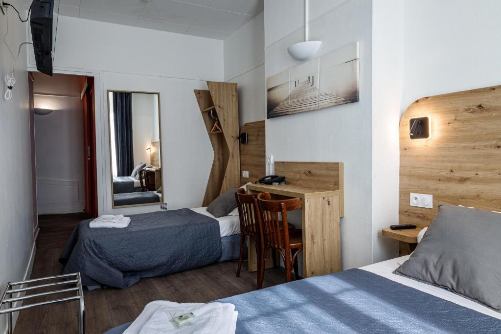 Habitación de hotel con 2 camas, escritorio y espejo. en Hotel Du Dauphiné, en Lyon