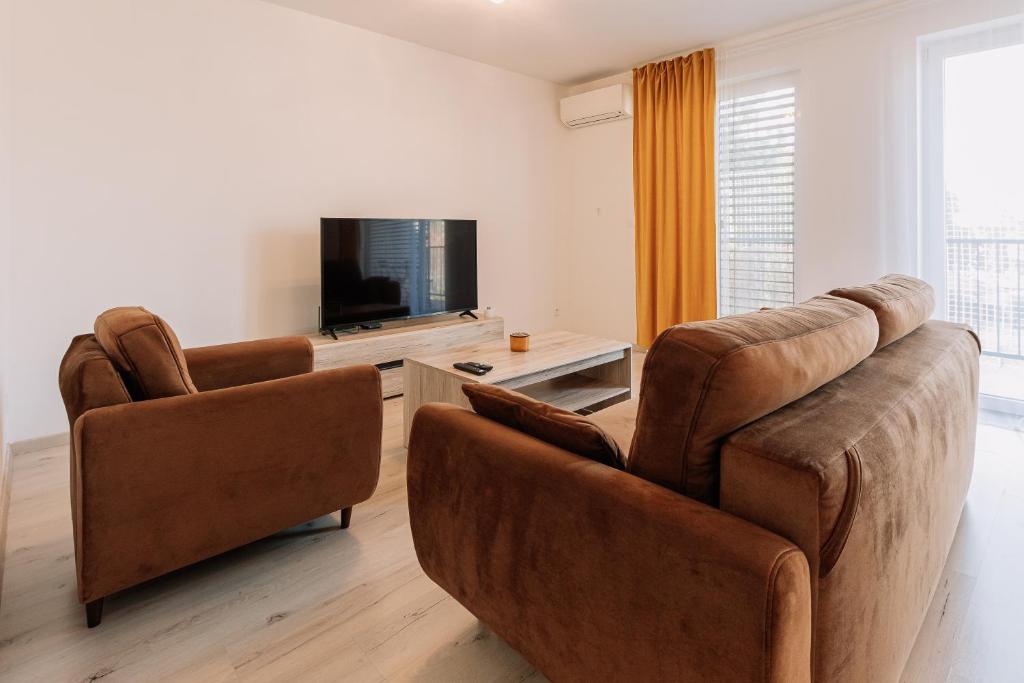 uma sala de estar com 2 cadeiras e uma televisão de ecrã plano em Sunrise Apartments em Senec