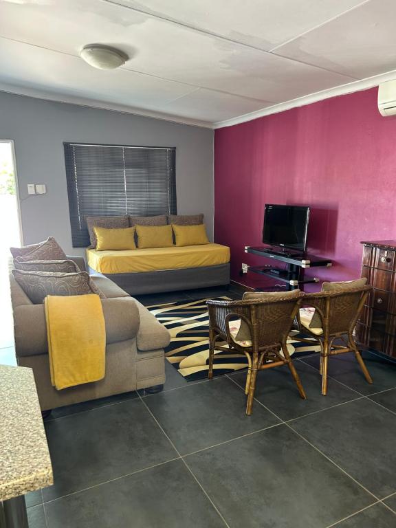 ein Wohnzimmer mit einem Sofa und einem Bett in der Unterkunft Mels Place in Bloemfontein