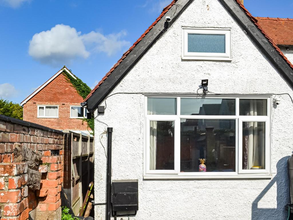 una casa bianca con finestra e muro di mattoni di Dormys Cottage a Skegness