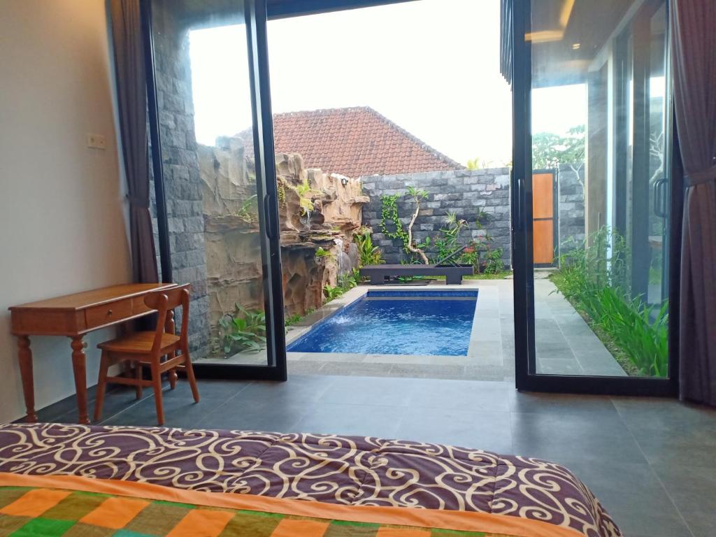 een slaapkamer met uitzicht op een zwembad via een glazen schuifdeur bij Semanggi Private Villa in Ubud